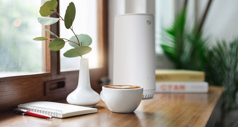 Rio router on a wooden desk by a window, next to a coffee and a notebook